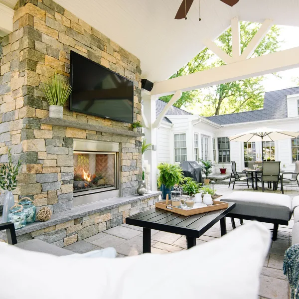 Gas-burning fireplace installed in outdoor patio and featuring a TV