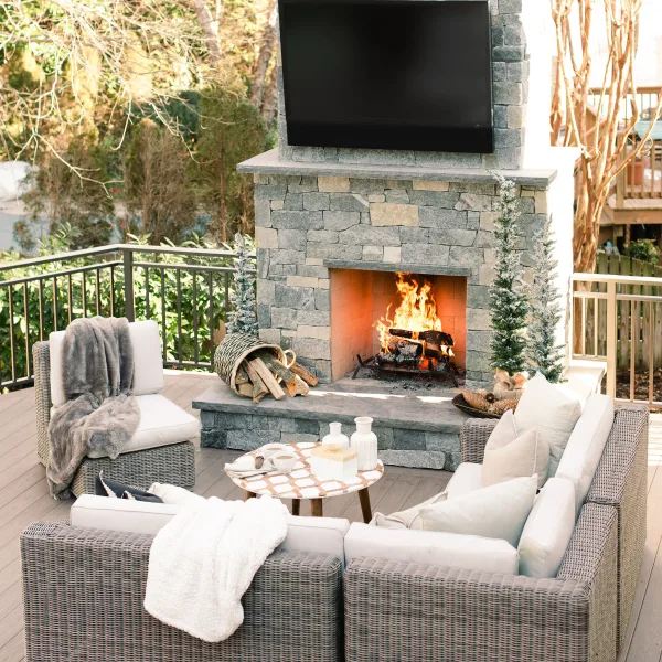 Furnished back deck in front of an outdoor fireplace and TV