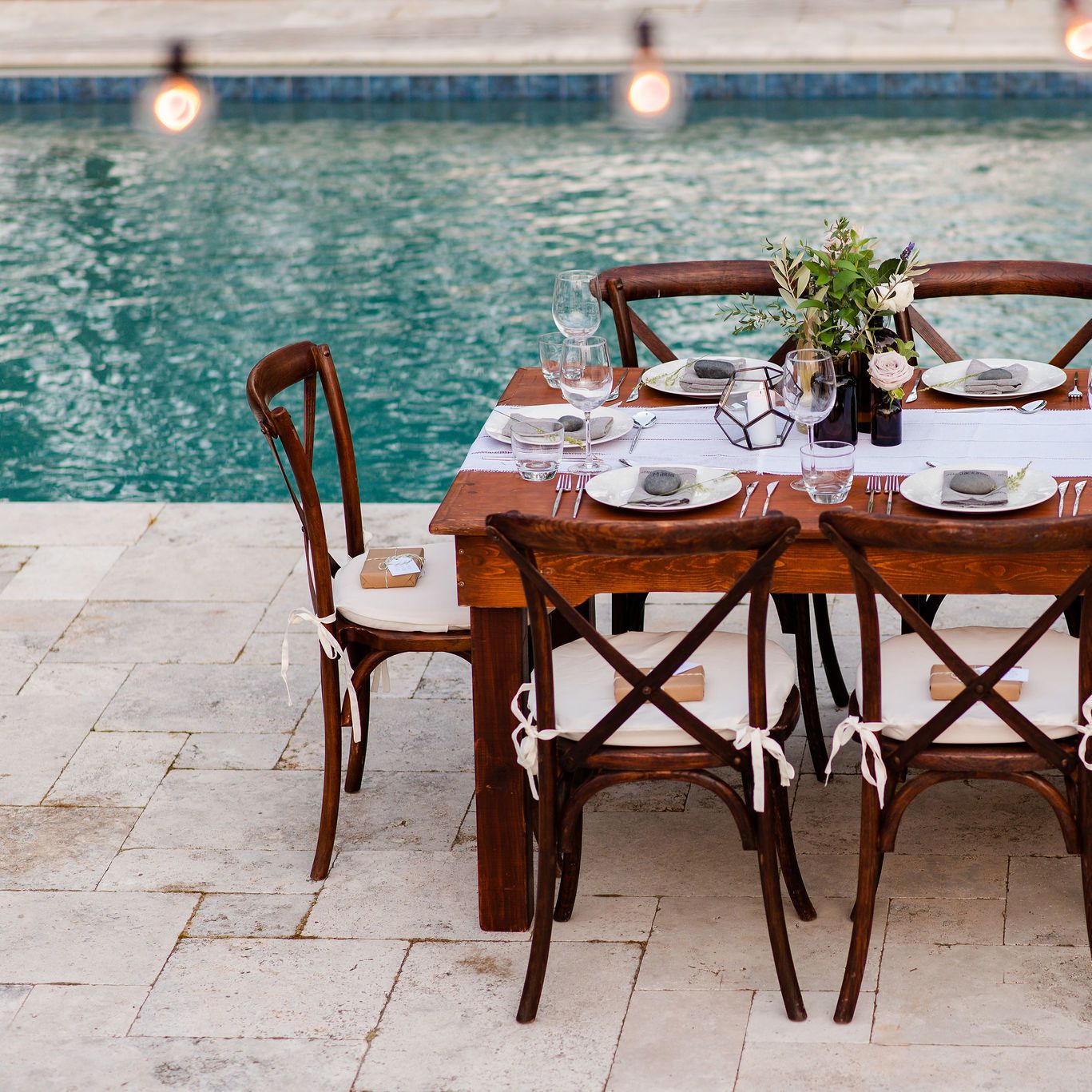 elegant dining table on a travertine patio next to a pool