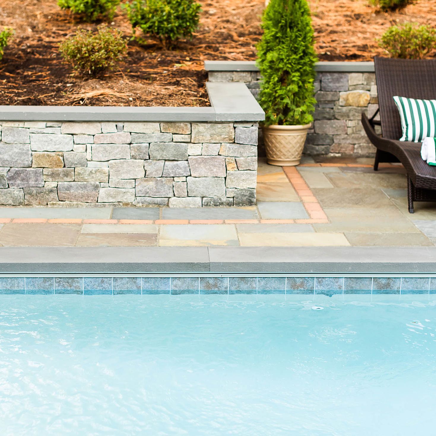 beautifully laid paver patio between retaining wall and underground pool