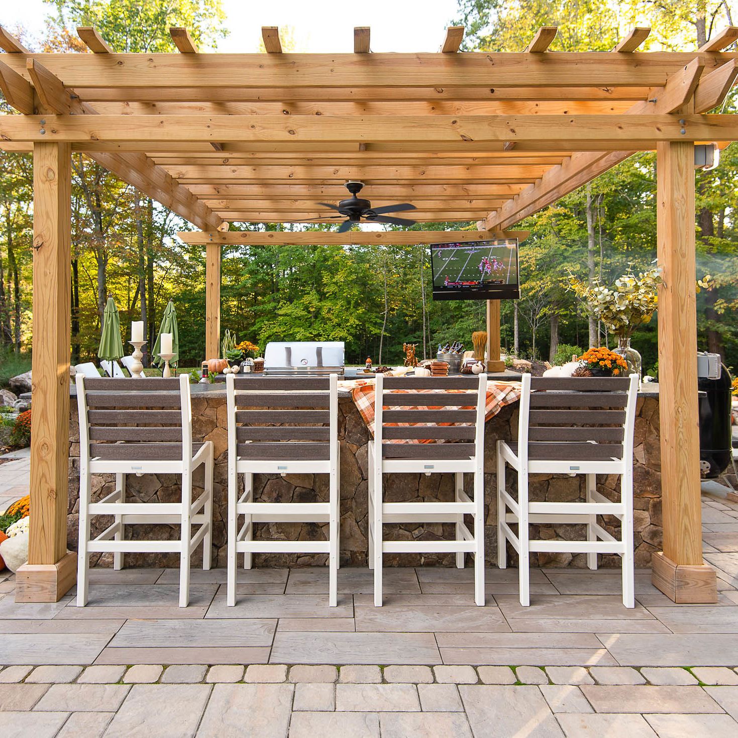 Pergola covered outdoor kitchen with four bar chairs